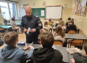 Policjant pokazujący karty dwóm uczniom