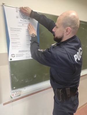Policjant zawieszający plakat